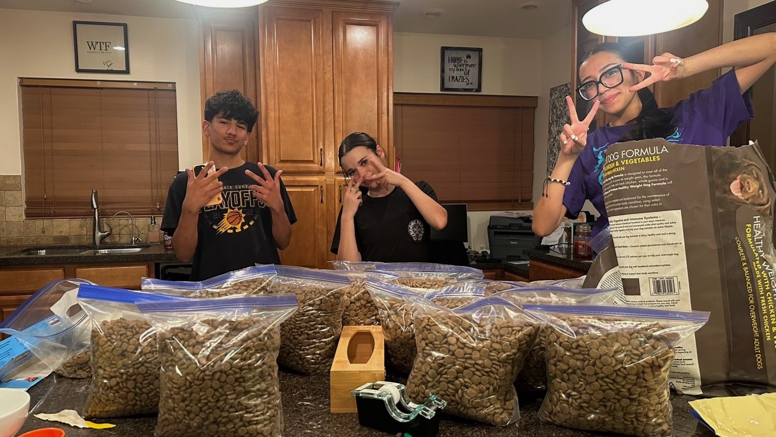 Three teens posing with dog food bags