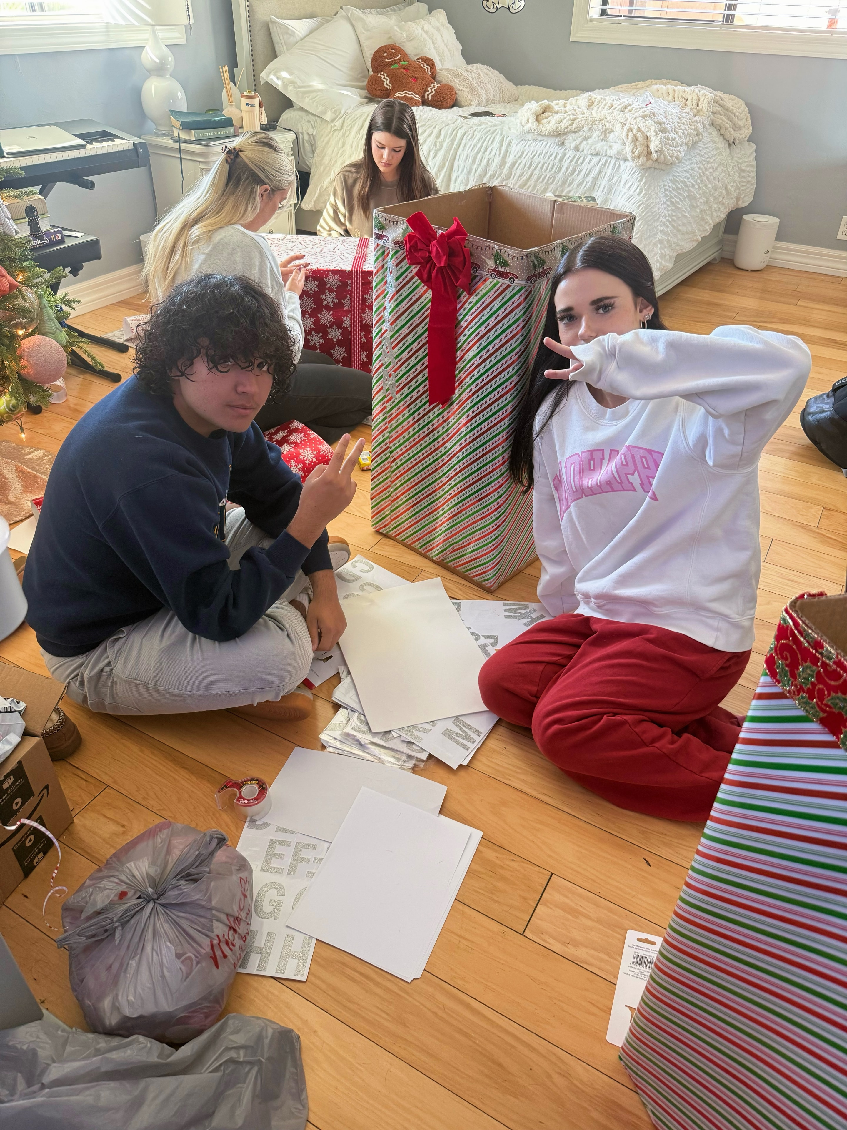 Friends opening holiday gifts in bedroom